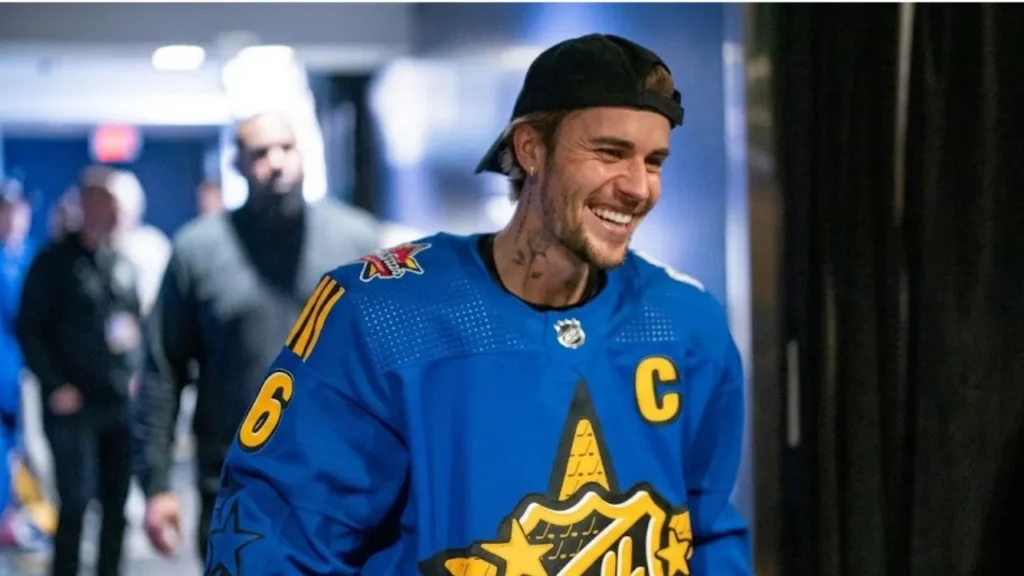Justin Bieber smiling on stage at the 2026 NHL Draft alongside NHL Commissioner Gary Bettman