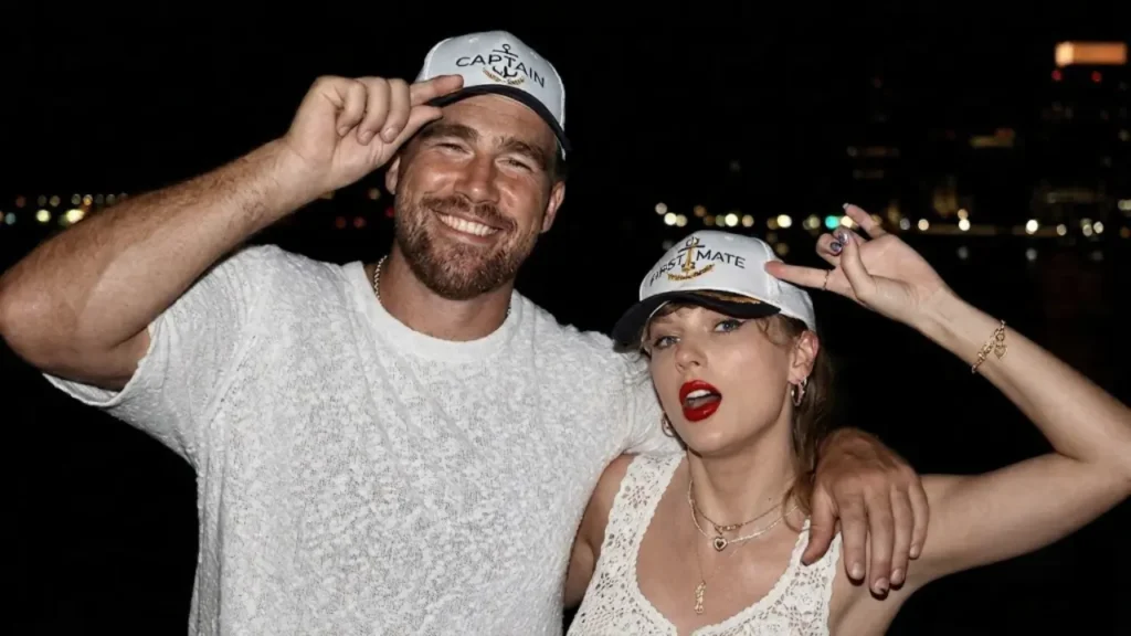 Taylor Swift flashing her engagement ring on stage next to Travis Kelce at a summer music performance.
