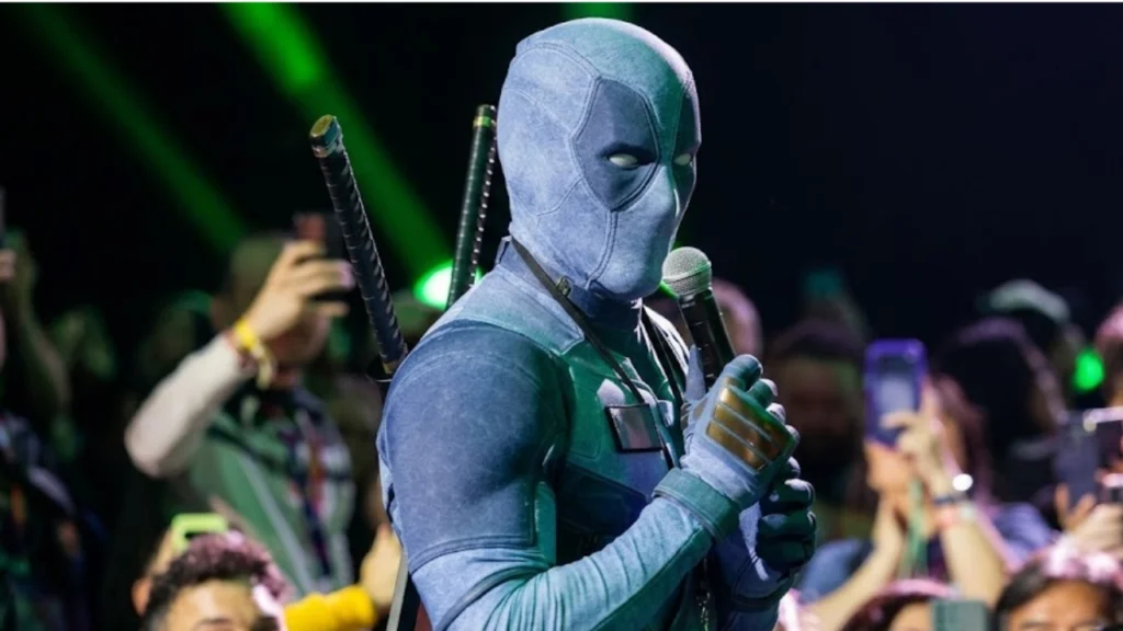 Ryan Reynolds wearing a grey and black Deadpool suit in the audience at San Diego Comic-Con.