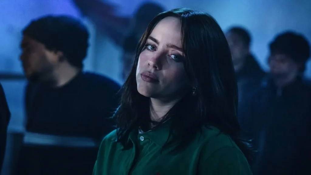 Billie Eilish singing on stage in front of a giant crowd during her Hit Me Hard and Soft tour