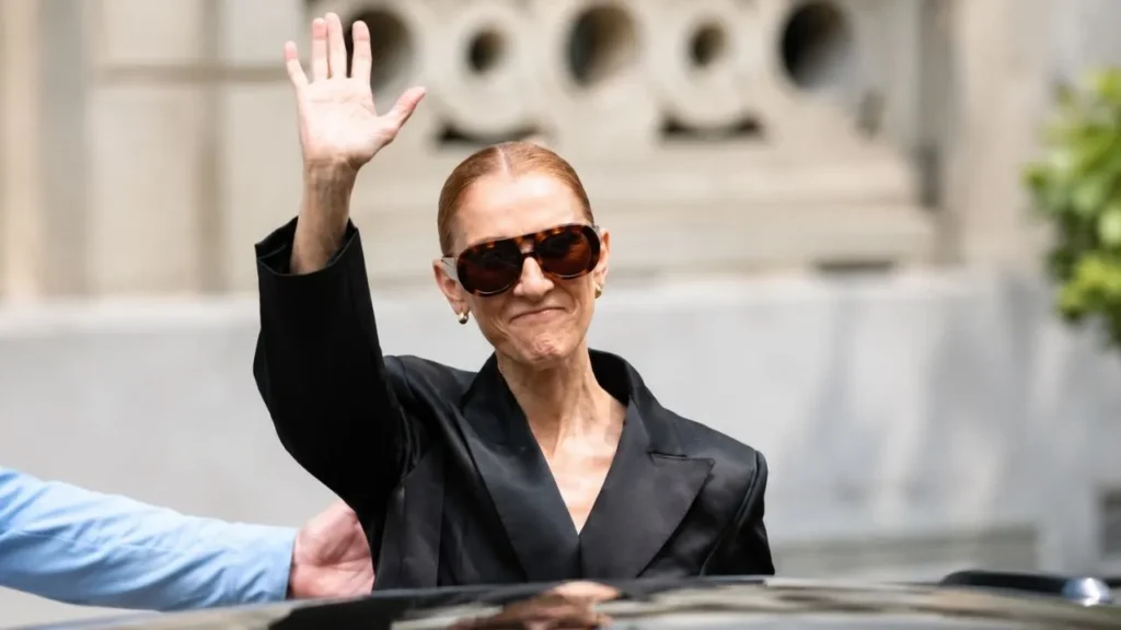 Celine Dion wearing an elegant black gown performing live under dramatic stage lights in Paris