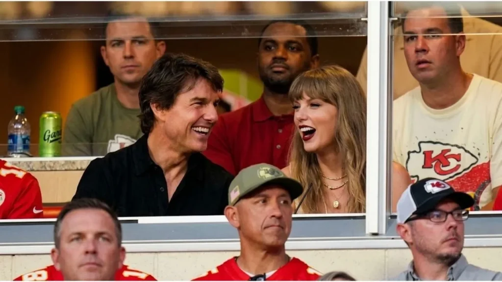 Tom Cruise and Taylor Swift laughing together inside a VIP stadium box at Arrowhead Stadium