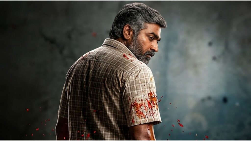 Indian actor Vijay Sethupathi speaking at a press event in a brown shirt with a microphone